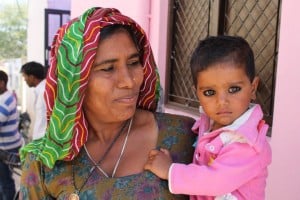 A mother applies a black paint on her child’s eyes to protect her daughter.