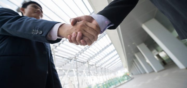 Business people shaking hands, view from below