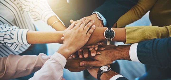 Closeup shot of an unrecognizable group of businesspeople joining their hands together in a huddle